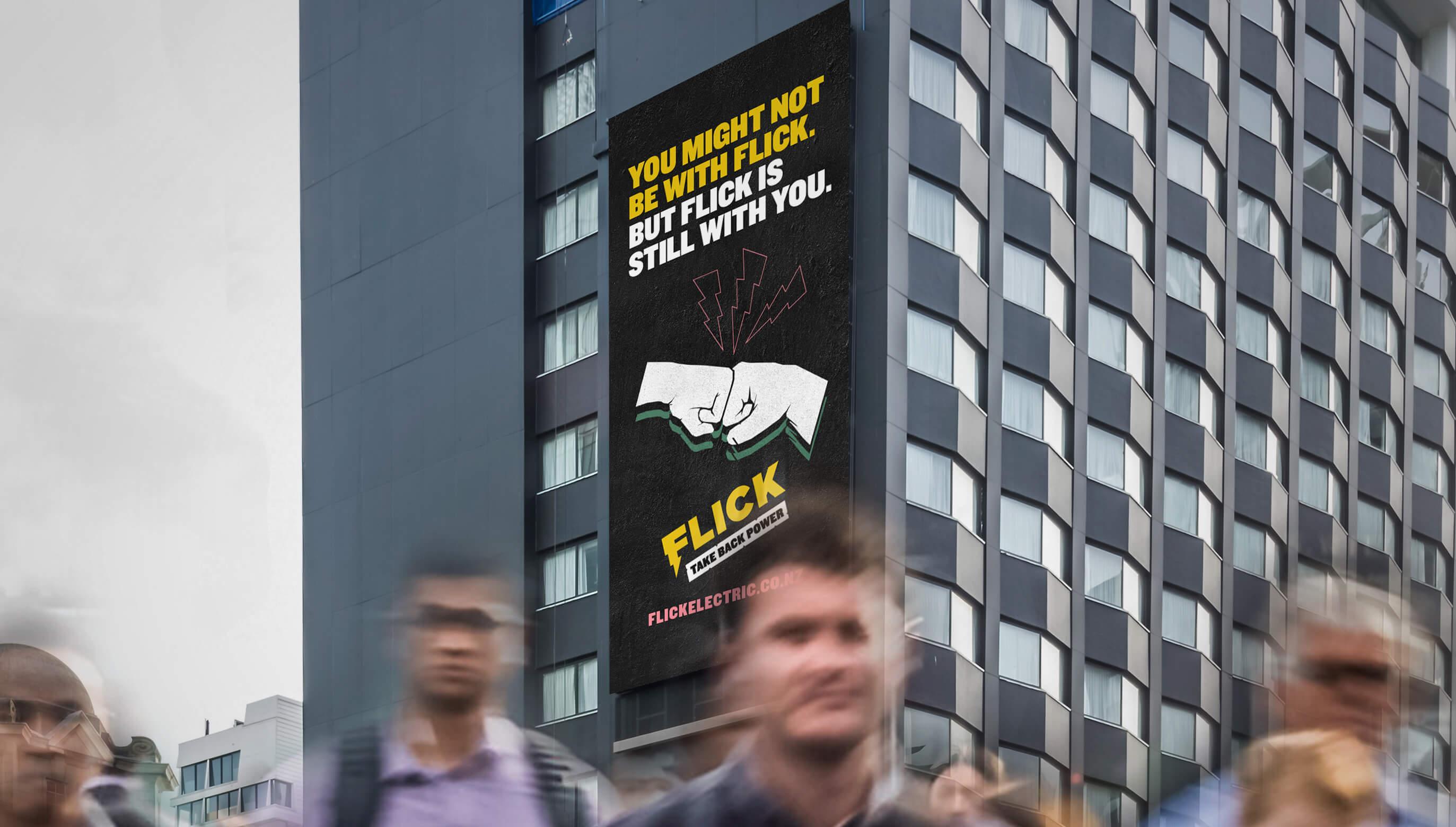 A photograph of people walking in front of a Flick Energy Billboard ad.